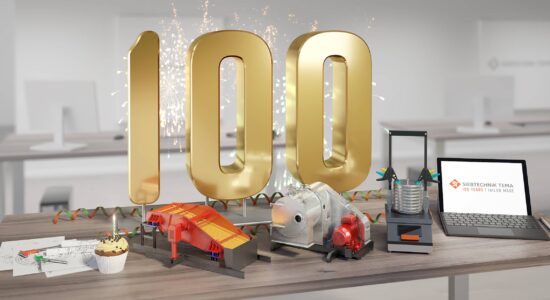 100 years SIEBTECHNIK TEMA, office with a desk on which a big golden 100 is standing, in front of it are models of some machines, a construction sketch and a laptop. The machines are a centrifuge, a screening machine and a test sieve shaker.